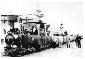 A narrow gauge train  is ready to depart from Swakopmund. In the background the Swakopmund Station Building is still under construction efore its official opening in mid-1902.
