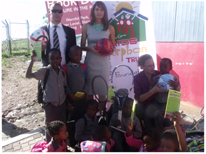 Mr Paul Sauerwein, (standing left) Principal of Otjomuise Primary School, Dr Christina Swart-Opperman, founder of the CSO Aids Orphans Foundation Trust, and Izan Engelbrecht, (seated right) with the Grade One learners of Otjomuise Primary School happily showing the books and assorted sports kit donated to the children by the Trust. (Photograph by Mandisa Rasmeni)