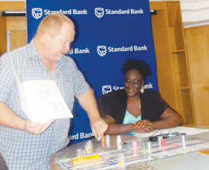 Anton du Preez, founder and Chairman of the Youth Entrepreneurship Seminar Trust (YES Trust), demonstrating how the business simulation game works to help learners become more business orientated and to make learning interesting. Observing the demonstration is Surihe Gaomas-Guchu, PR and Communications Manager at Standard Bank.. (Photograph by Mandisa Rasmeni)
